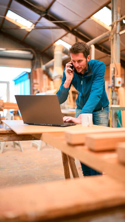Handwerksbetrieb im Arbeitsalltag zwischen Telefon, Laptop und Werkstatt